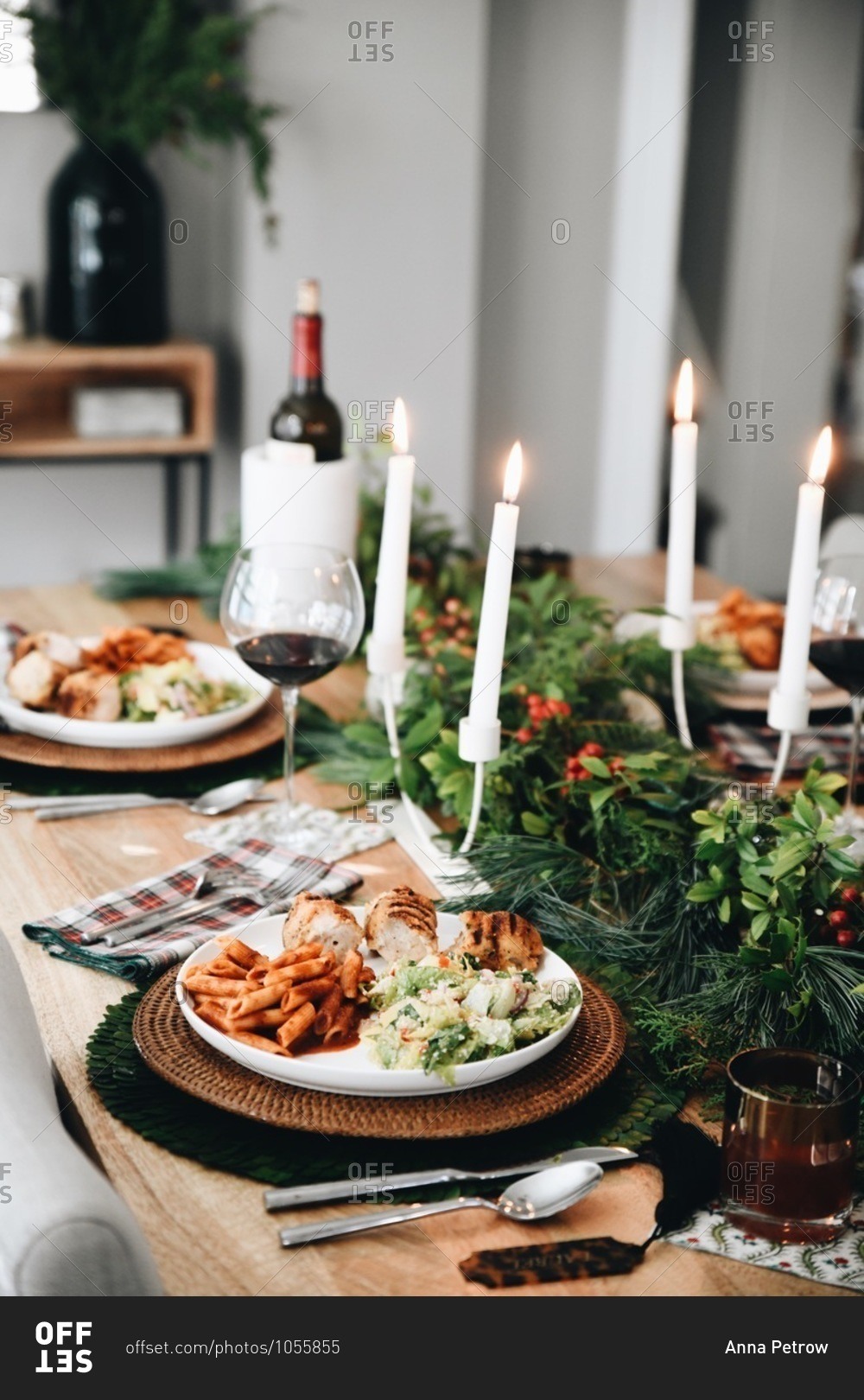 Food served on a dinner table set for a small holiday party with candles and wine