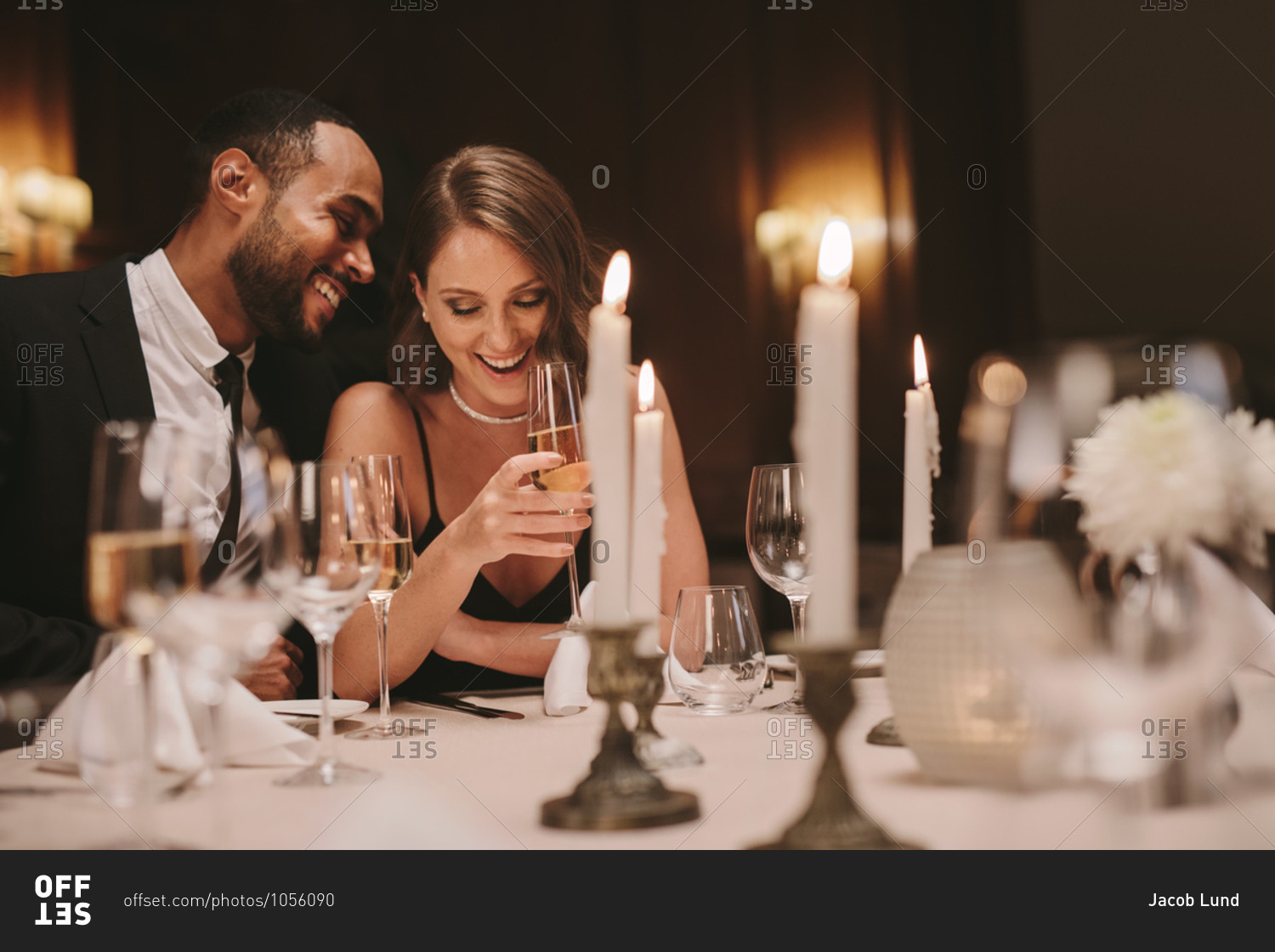 Young couple sitting at dining table with candles having wine. Loving man and woman at a gala dinner party.