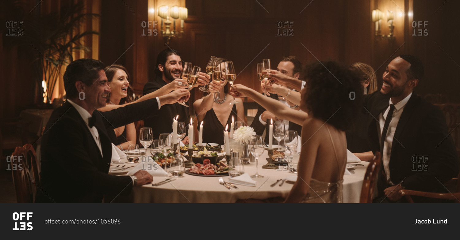 Group of people toasting drinks at a gala party. Multiracial friends enjoying new years party with drinks.