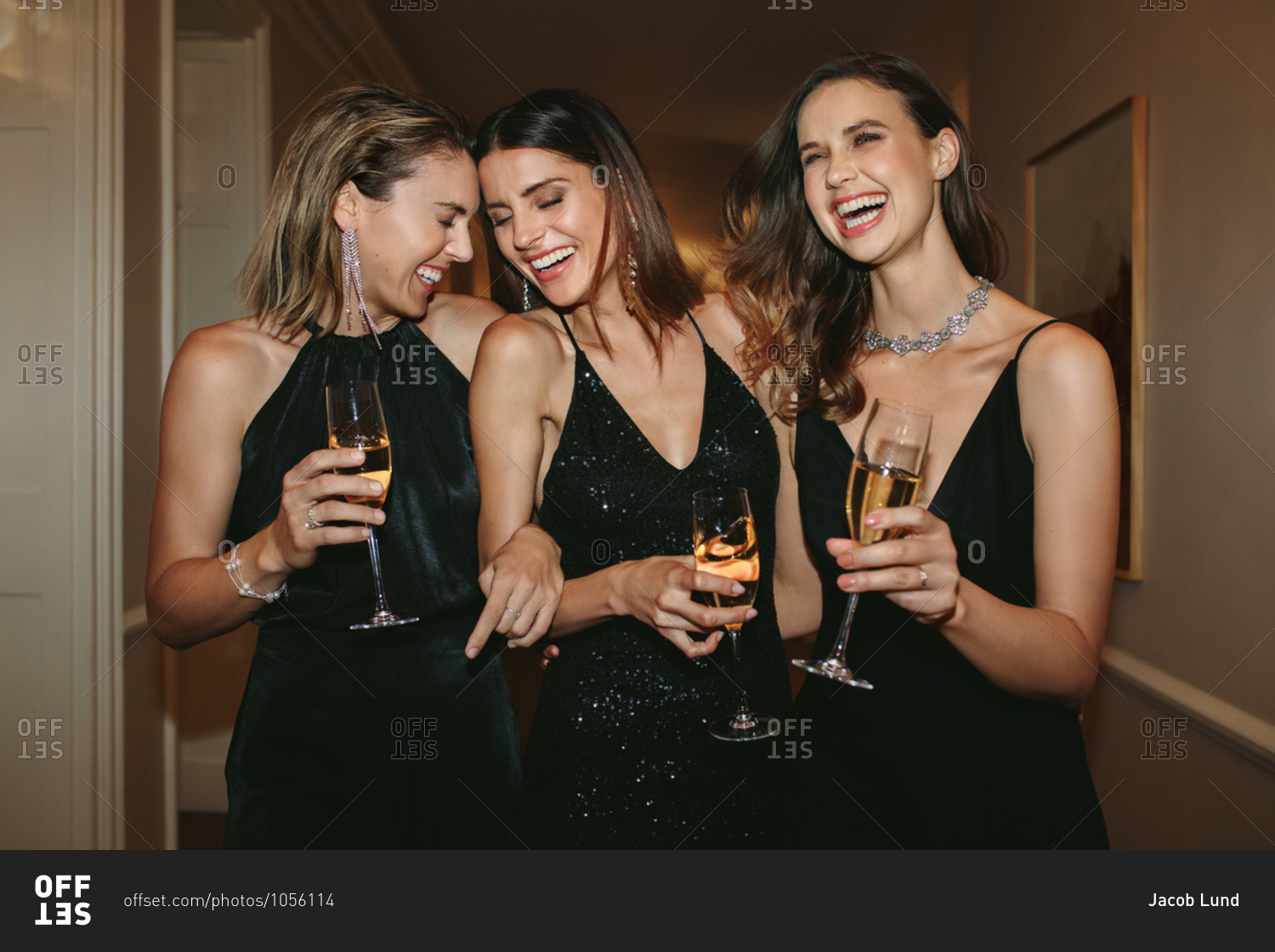 Group of women with champagne glasses walking in corridor. Best friends enjoying at a gala night party.
