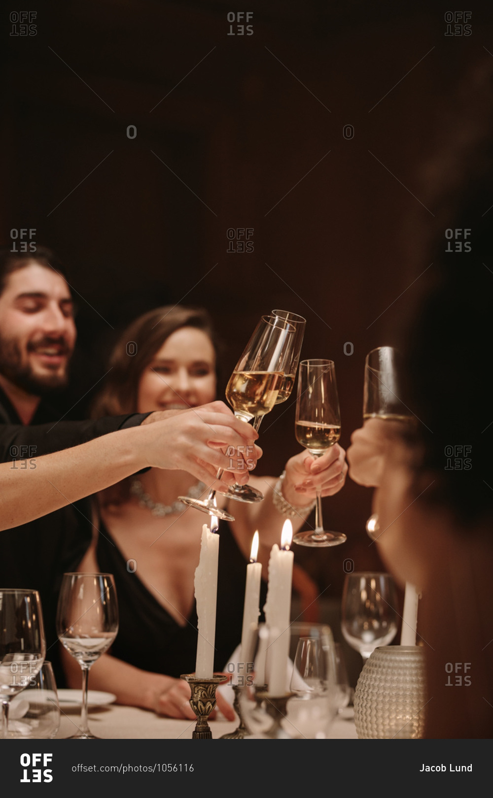Group of men and women celebrating party with champagne. High society people at a dinner party toasting drinks.