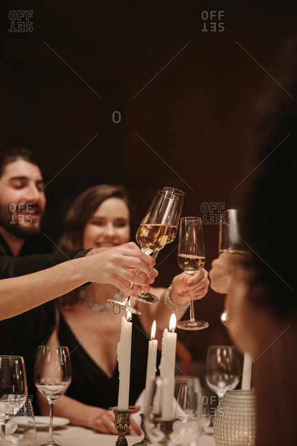 Group of men and women celebrating party with champagne. High society people at a dinner party toasting drinks.