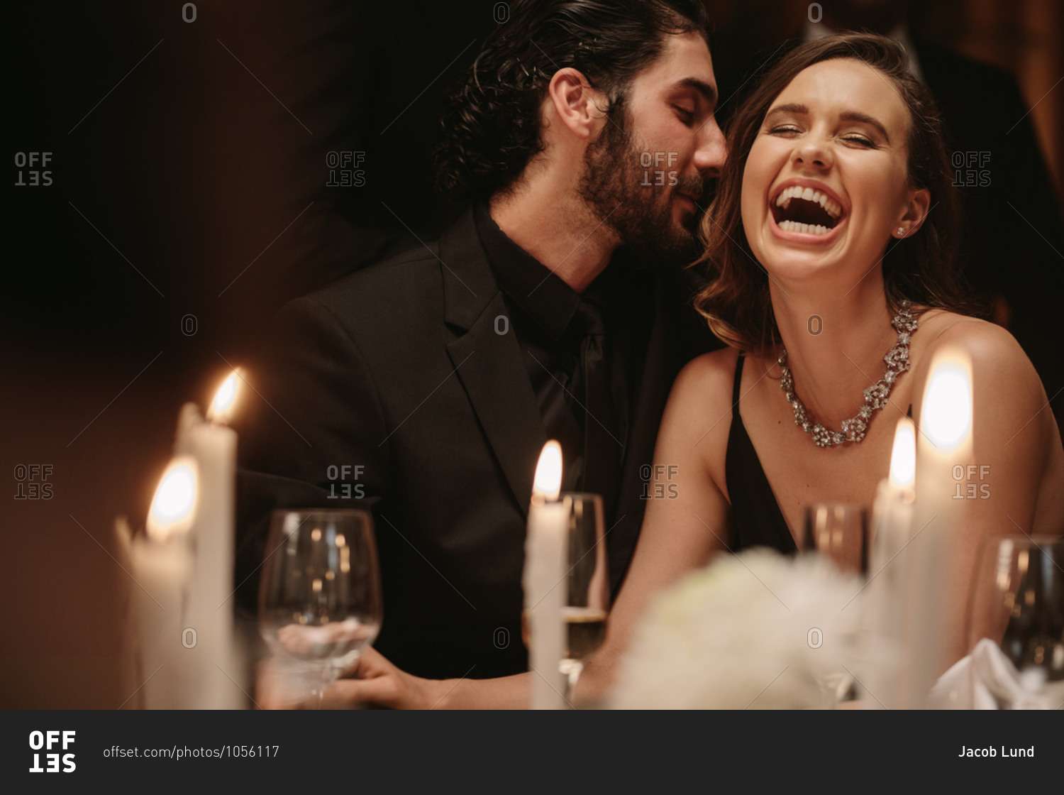 Man whispering in to woman\'s ear at a dinner party. Loving couple having a fun at a gala dinner event.