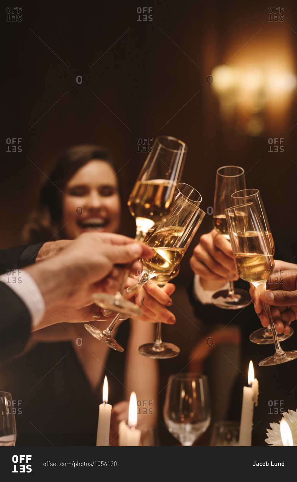Group of men and women enjoying a dinner party, toasting champagne glasses. Group of friends having drinks at gala night.