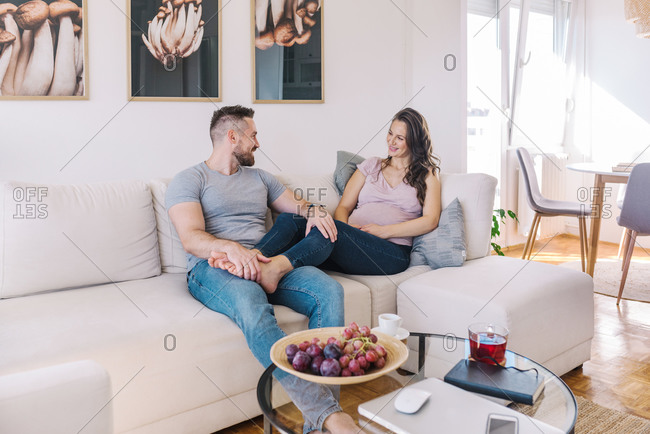 Young couple expecting their first child relaxing on sofa together