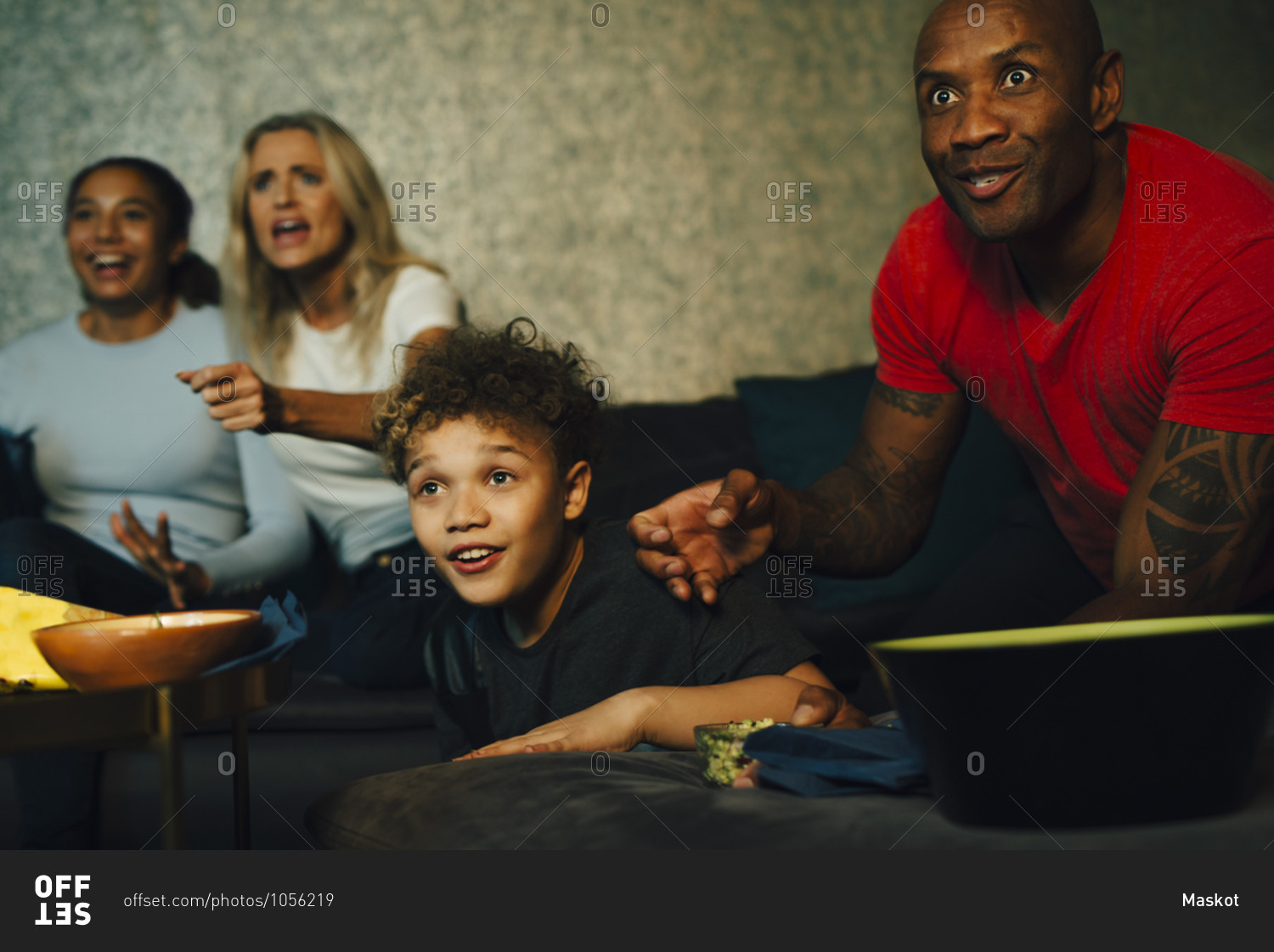 Excited sports fans watching TV together at night