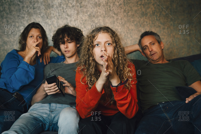 Girl praying while watching sports with family at home