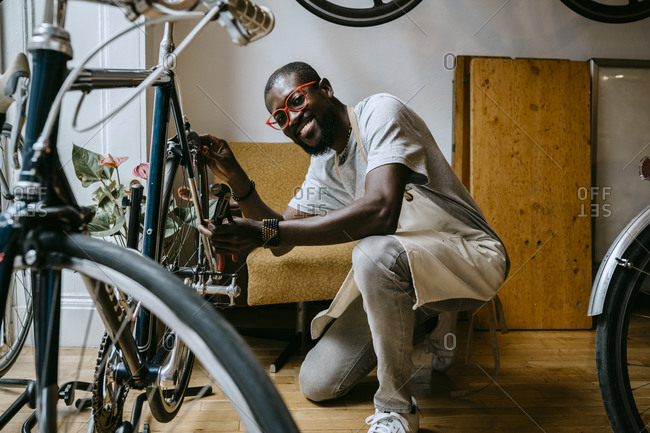 Portrait of smiling male owner repairing bicycle in workshop
