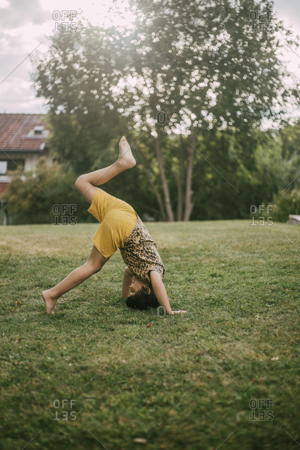 Side view of girl practicing headstand in yard