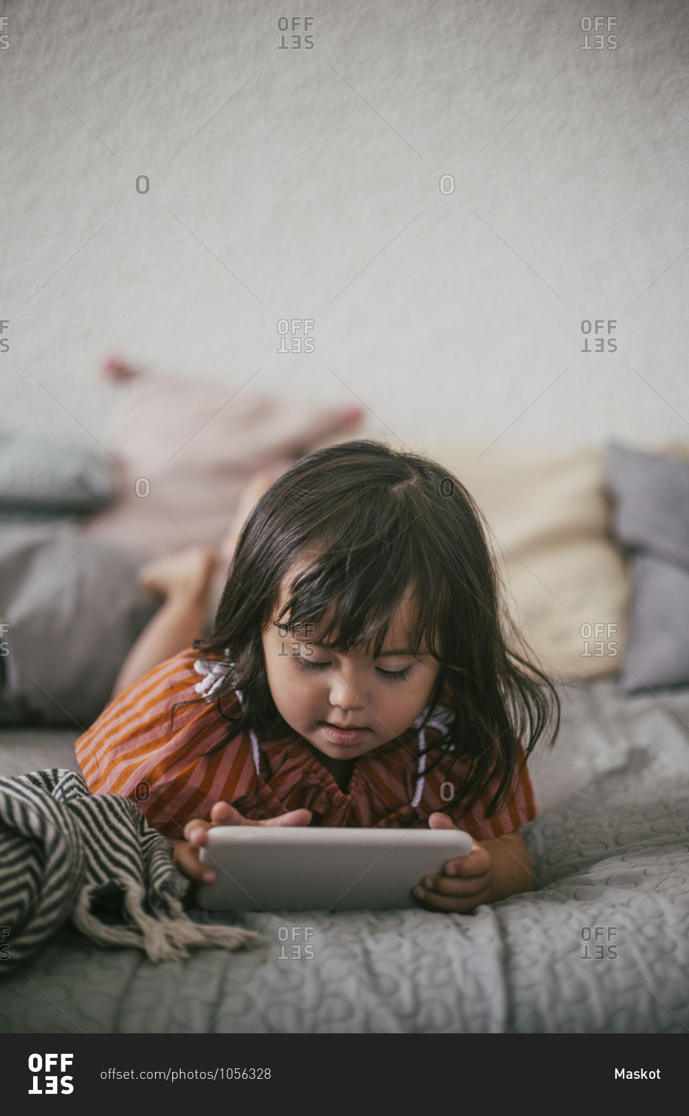 Down syndrome girl using digital tablet while lying on sofa at home