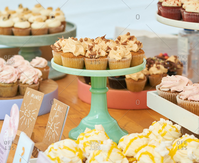 A bakery counter filled with vegan cupcakes on cake stands