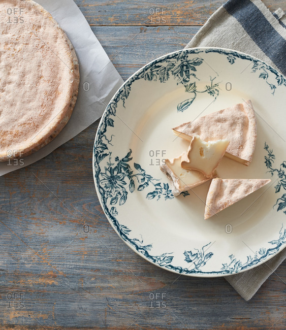 Slices of cheese with an unusual pink rind on a vintage French plate