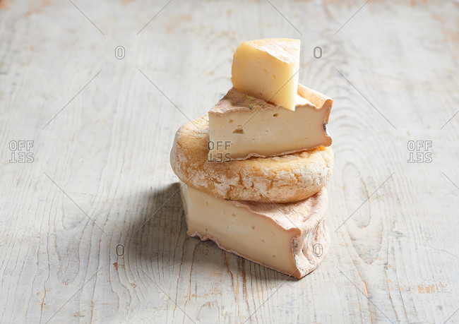 A stack of sliced of artisanal cheese on a pale wooden surface
