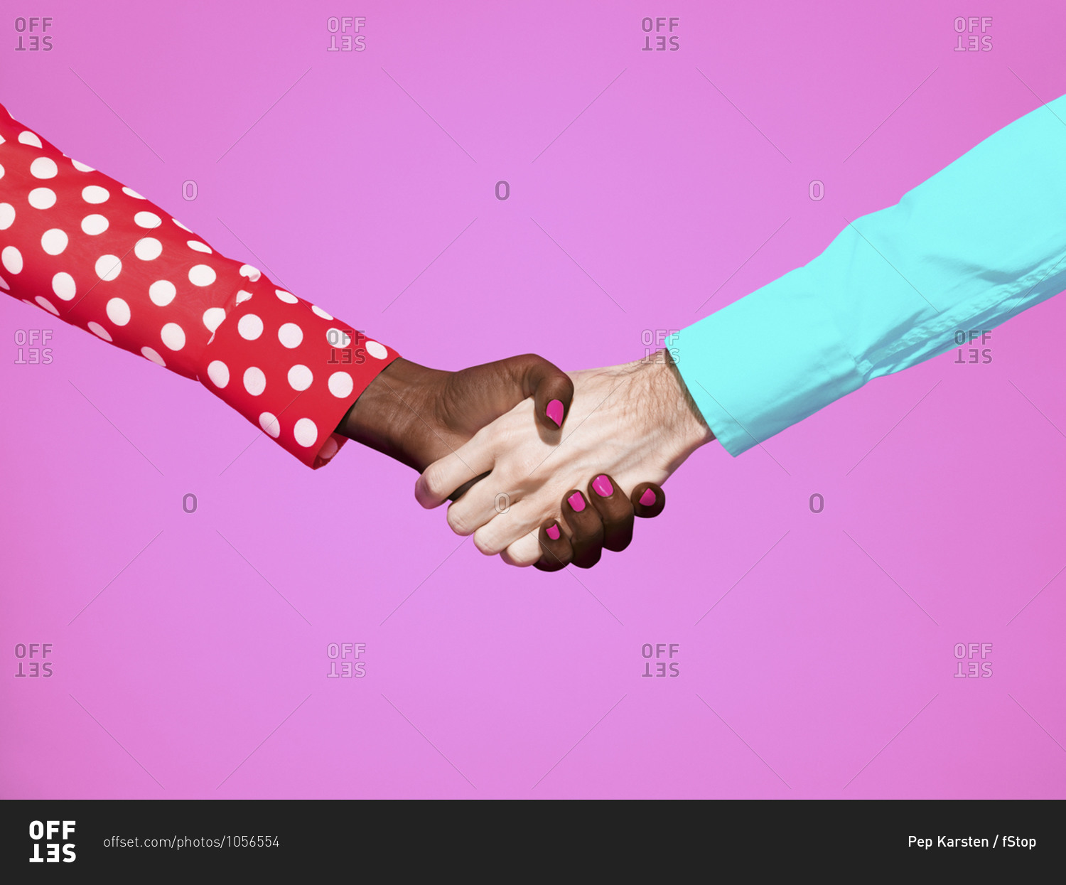 Multiethnic handshake on pink background