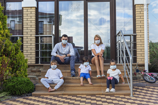 Portrait family in face masks on patio steps of house