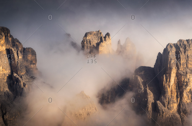From above of rough high rocky formations covered with mist under sky in daytime