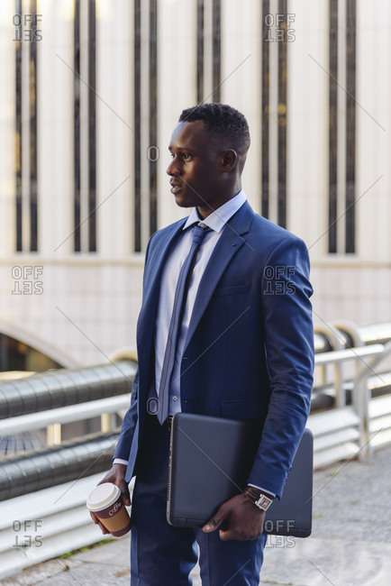 Full body side view of confident respectable african american businessman in formal outfit walking on street against contemporary buildings in modern downtown