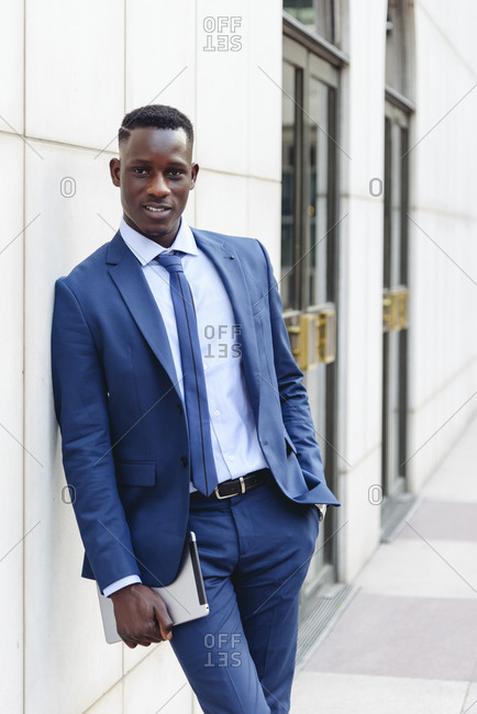 Low angle of serious African American male entrepreneur wearing classy suit  standing with hand in pocket