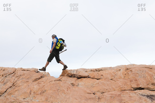 Senior man spending time in nature, walking in the mountains, walking by a cliff.