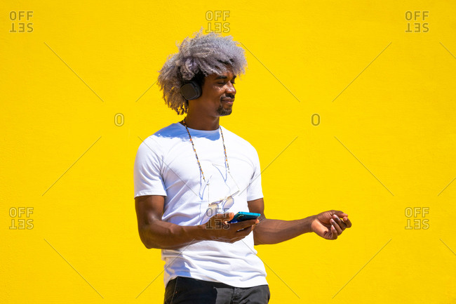 Black man with afro hair listening to music with headphones and dancing. concept of listening to music with headphones.