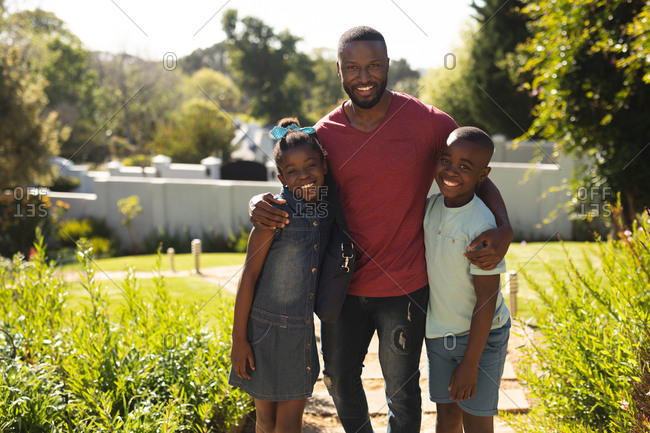 Portrait of African American father, daughter and son smiling while standing in the garden on a bright sunny day.
