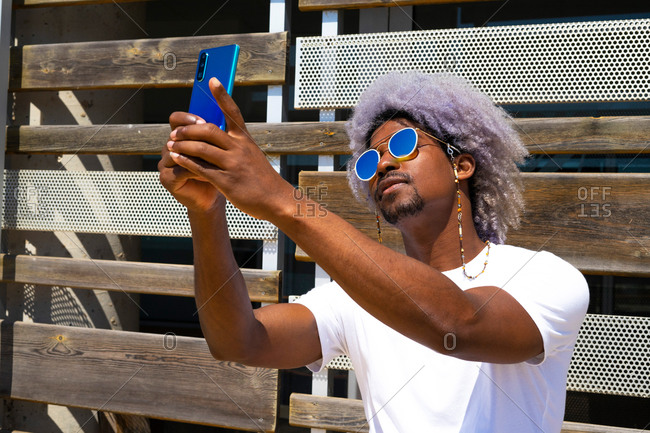 Black man with afro hair taking a selfie with his blue mobile. selfie concept.
