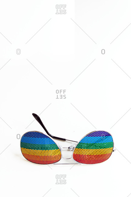 From above of sunglasses with lenses with lgbt flag placed on white table illuminated by sunlight