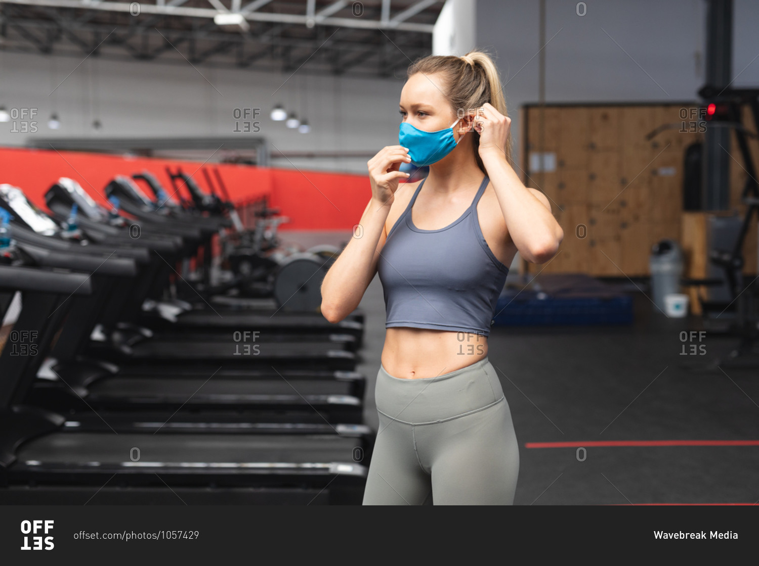 Fit caucasian woman wearing face mask in the gym.