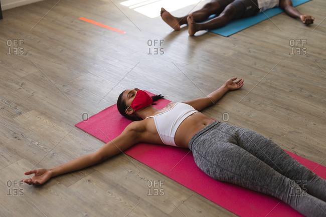 Lying on yoga mat young woman holding muscular man on lifting legs on  lesson in training room stock photo