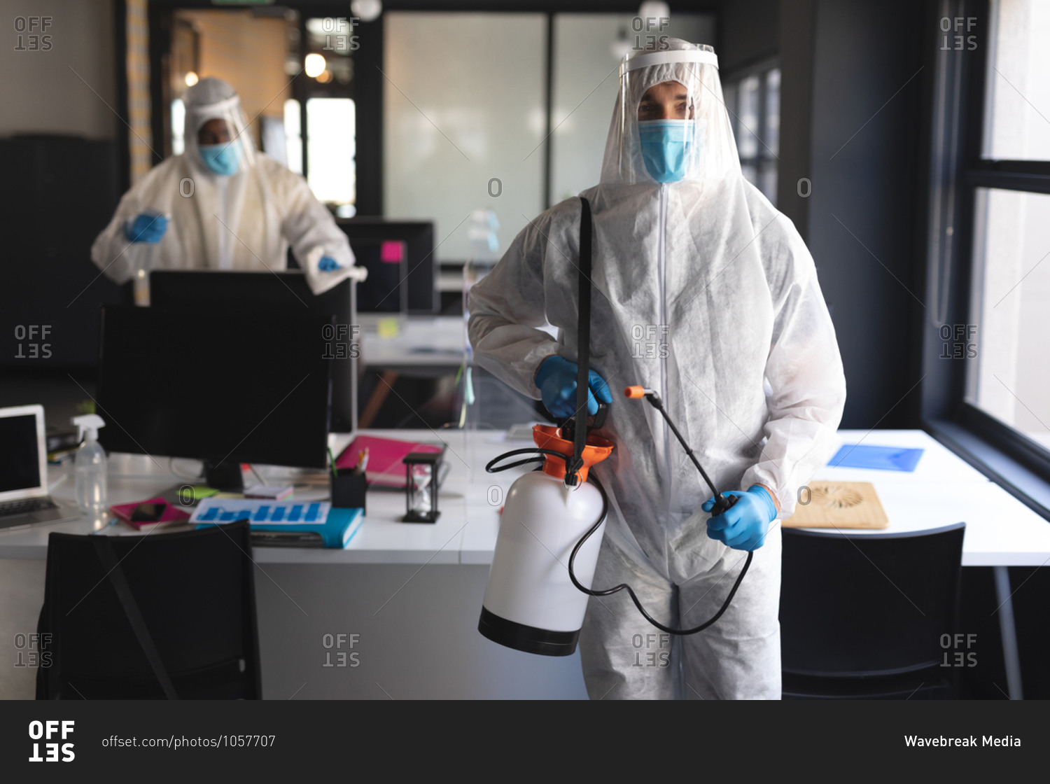 Portrait of male health worker at modern office. wearing face mask and protective clothes carrying disinfectant spray.
