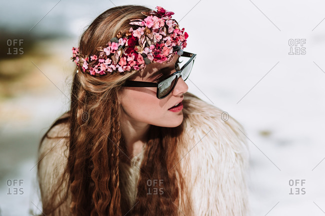 Attractive young long haired female in fur jacket and sunglasses with floral wreath on head