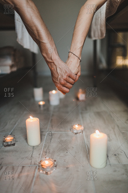 A couple in love hold hands in a spa atmosphere of romance candles