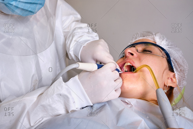 Close up of female dentist drilling tooth to patient