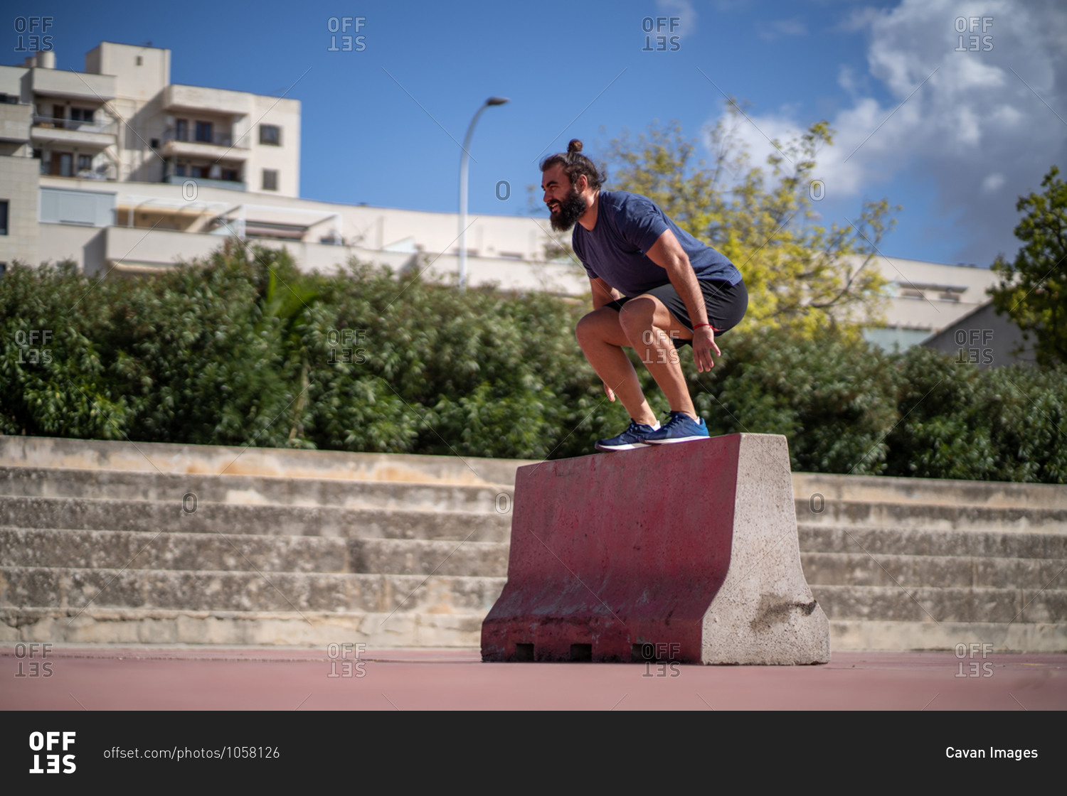 Man trains with squat jumps on a platform in the middle of a court