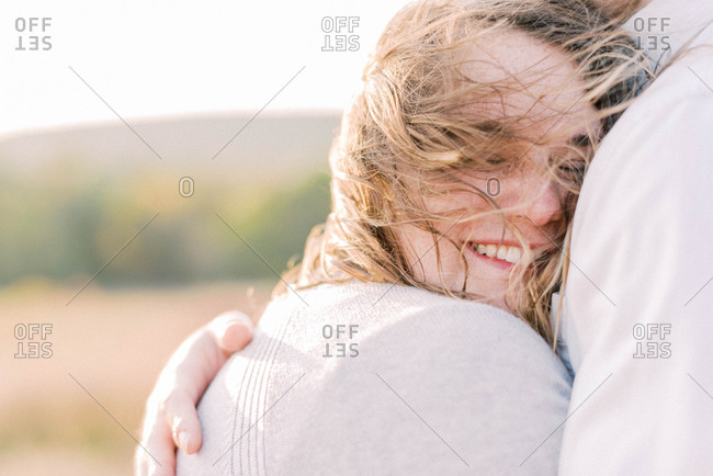 A beautiful woman being held by her husband on a windy day