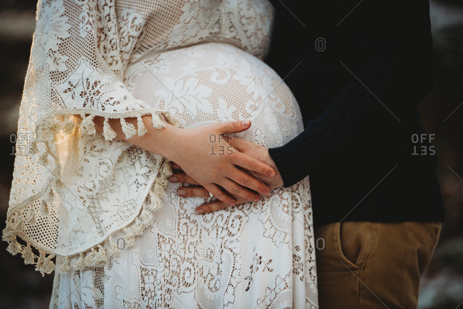 Close up of husband and pregnant wife hands touching belly outdoor