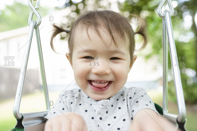 Close-up of Adorable Toddler Girl Smiling in Backyard Swing