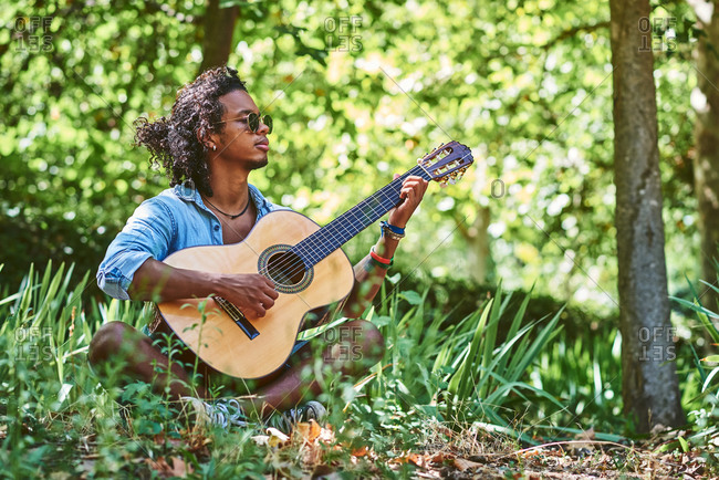 Musician practicing with the guitar in the field.