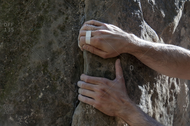The hands of the climber with a tape held to the rock.