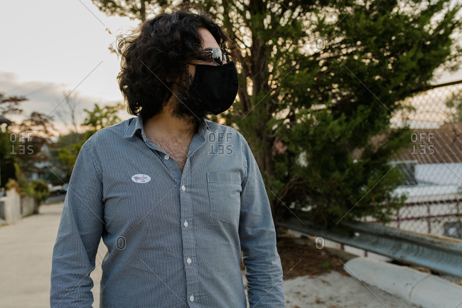 Man with mask and I voted sticker looking off camera