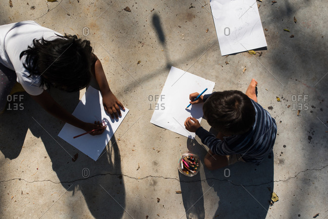 Children drawing on paper outside from above
