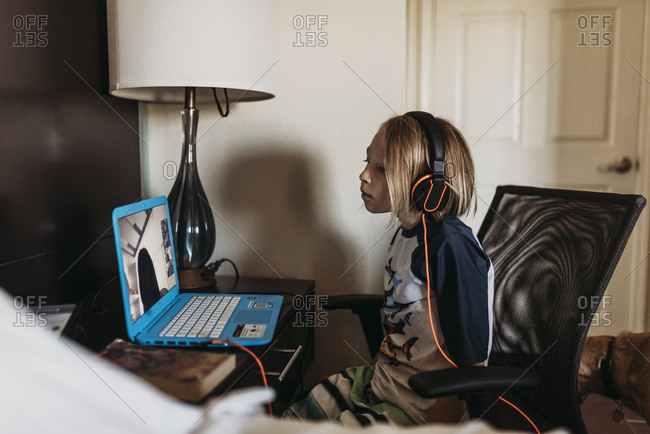 School age boy distance learning in hotel room during pandemic