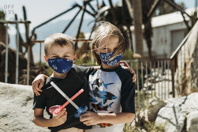 Close up portrait of young brothers with masks on outside on vacation