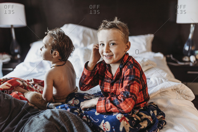 Young boy in pajamas sitting on hotel bed on vacation