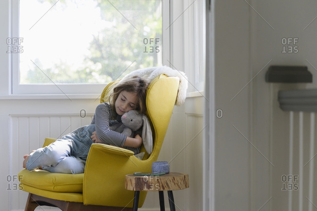 Girl (5-7) relaxing in armchair