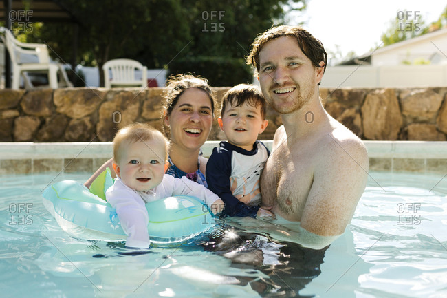 Portrait of parents with kids (2-3, 6-11 months ) standing in outdoor swimming pool