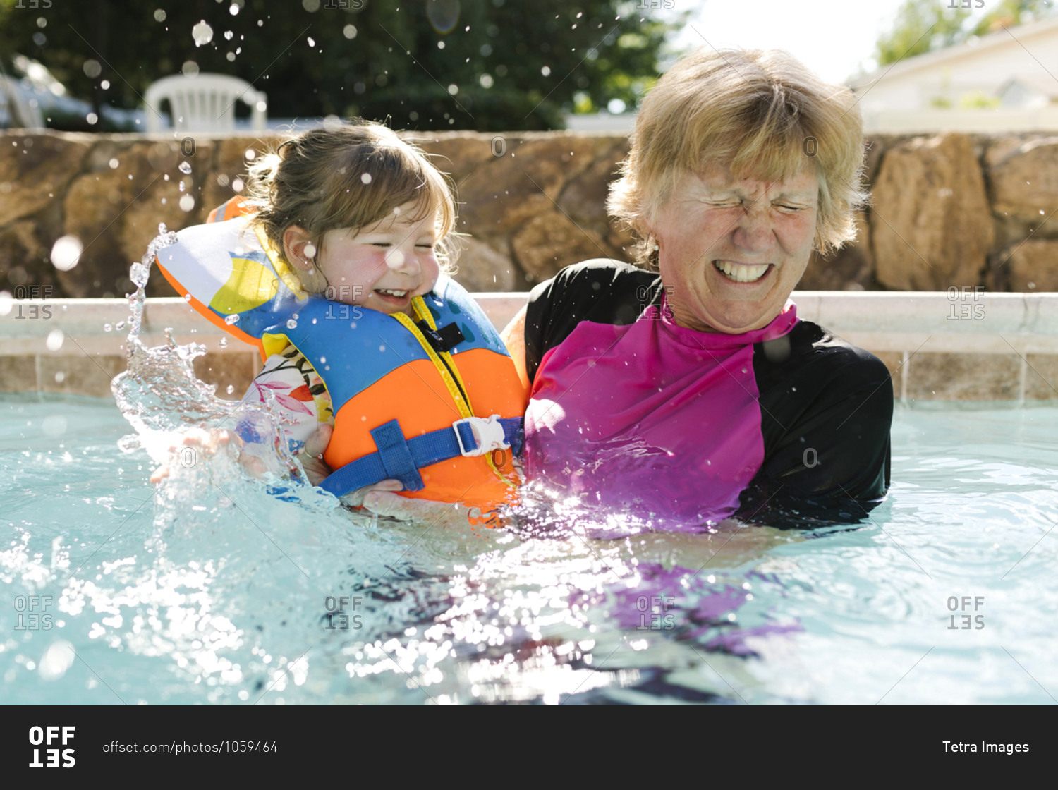 Grandmother playing with toddler girl (2-3) in outdoors swimming pool