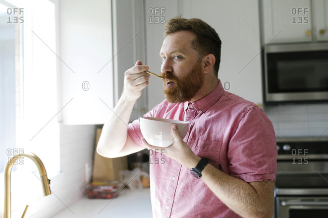 Man eating cereal breakfast in kitchen