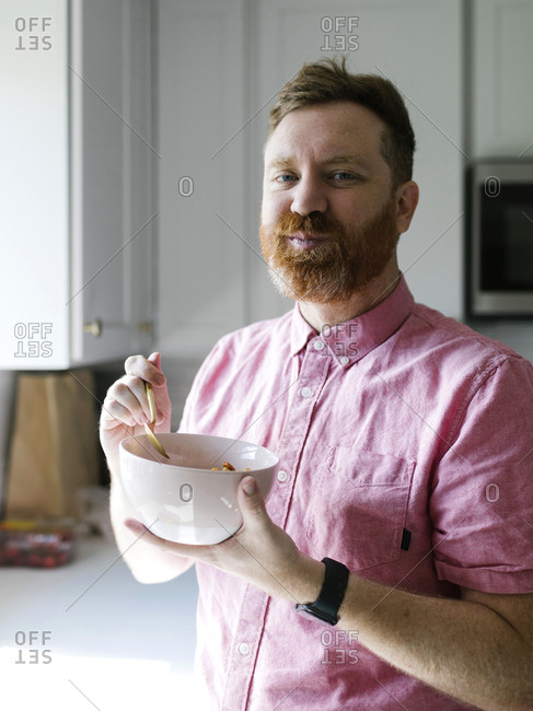 Portrait of man eating cereal breakfast in kitchen