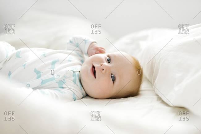 Baby boy (6-11 months) lying on bed
